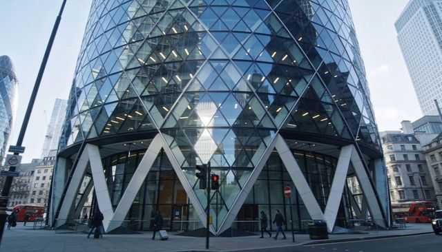 Contemporary glass tower reflecting city skyline with diamond facade and street pedestrians