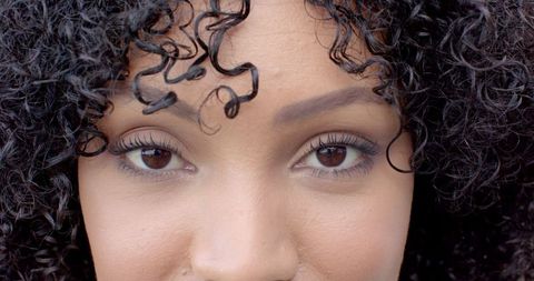 Close-Up Portrait of Woman with Curly Hair Smiling Confidently