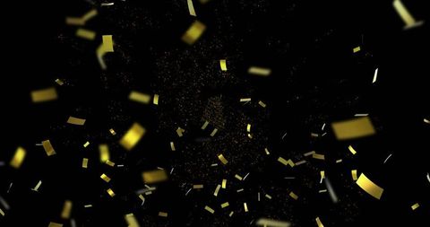Falling gold confetti strips over black backdrop with glitter dust and bokeh sparkle