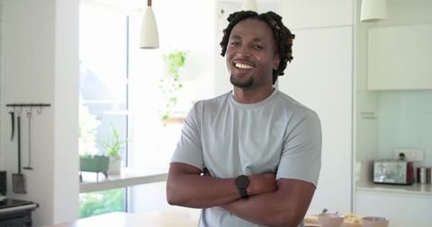 Confident african american man smiling in bright modern minimalist kitchen
