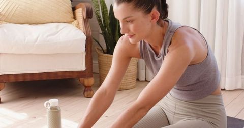Woman Practicing Yoga Stretch at Home in Bright Living Room