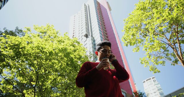 Man in Red Sweater with Coffee Against Urban Skyscraper Backdrop - Download Free Stock Photos Pikwizard.com