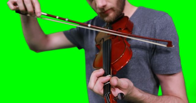 Male musician playing violin against green screen