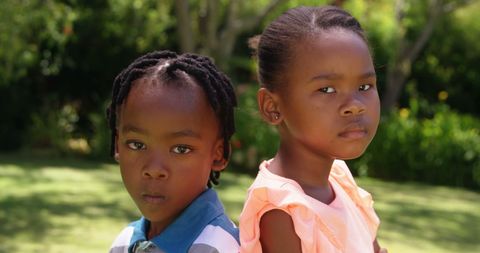 Two Serious African American Children Standing Together Outdoors
