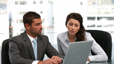 Business Colleagues Analyzing Data on Laptop in Office Environment