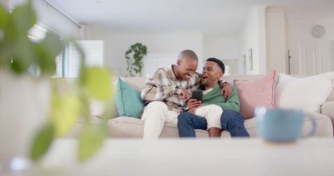Happy Gay Couple Relaxing and Laughing on Cozy Couch