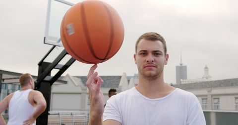 Caucasian athlete balancing basketball on urban court
