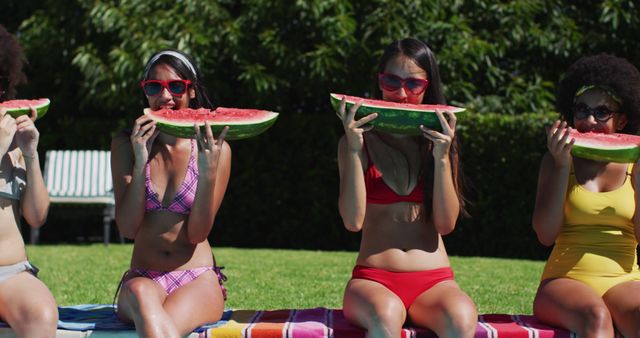 Portrait of group of diverse girls eating watermelon while sitting by the pool. youth friendship and pool party concept