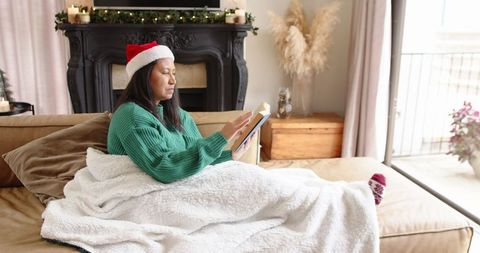 Senior Woman Relaxing with Tablet by Christmas Fireplace
