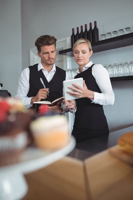 Waiters using digital tablet at counter in restaurant