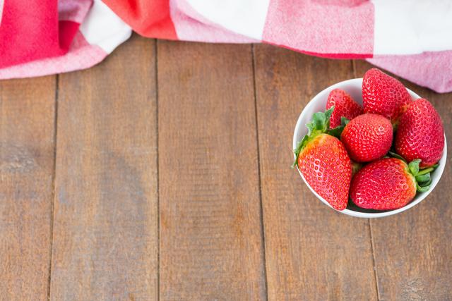 Bowl of fresh strawberries on wooden board