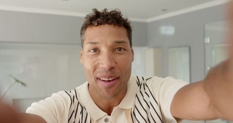 Man Holding Camera in Modern Living Room, Smiling Confidently
