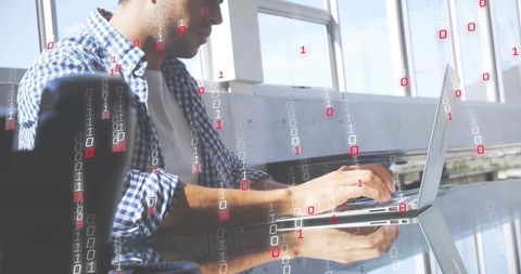 Developer typing on laptop with binary code overlay in office workspace for cybersecurity