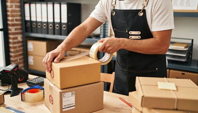 Sealing Boxes for Shipment: Fulfillment Worker Taping Labeled Parcels in Packing Area