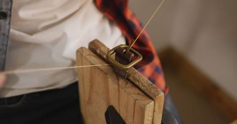 Skilled craftsman hand-stitching leather belt