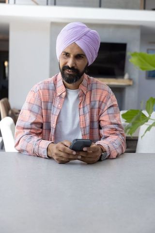 Relaxed indian man in morden living room using smartphone