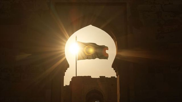 Sunlit flag waving through historic horseshoe arch gateway at fortress dawn