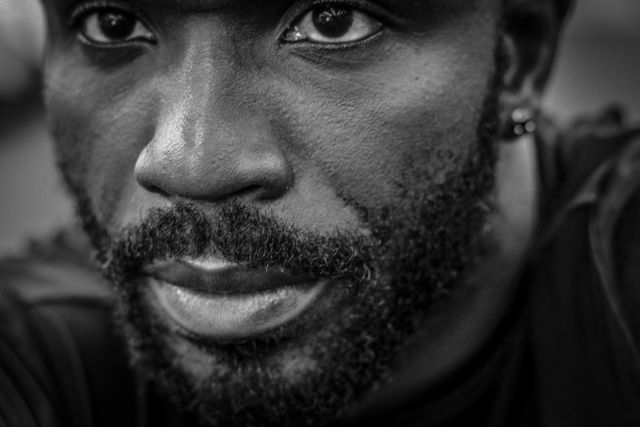 Pensive African American man with a beard in an introspective moment. Black and white close-up highlights facial features, beard, and emotions. Ideal for projects about diversity, human emotions, introspection, men, and realism in photography.