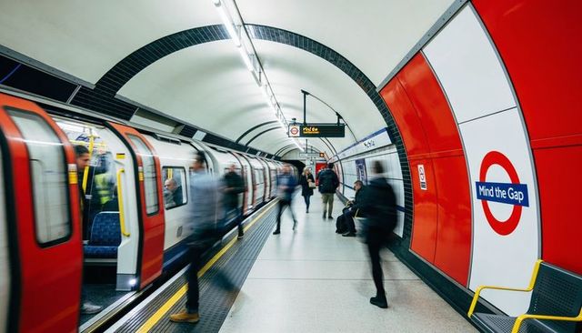 London underground commuters boarding and walking on tube platform with mind the gap
