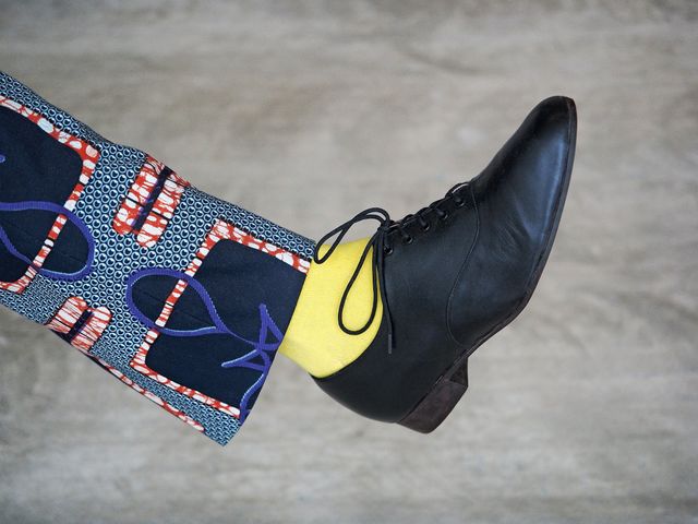 Person showing unique fashion style by wearing yellow socks, patterned pants, and black shoes. Ideal for use in fashion blogs, clothing advertisements, style guides, and social media posts about modern and eclectic fashion trends.