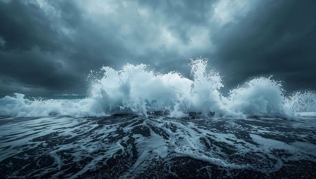 Crashing storm wave surging onto black sand shore under dramatic storm clouds