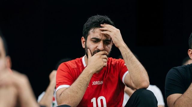 Male athlete looking distressed on bench wearing jordan 10 red jersey, sideline tension