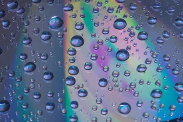 This visually striking image showcases water droplets on a multi-colored surface, displaying a beautiful rainbow effect. Ideal for use in presentations, backgrounds for digital art, design projects, and visually engaging web content.