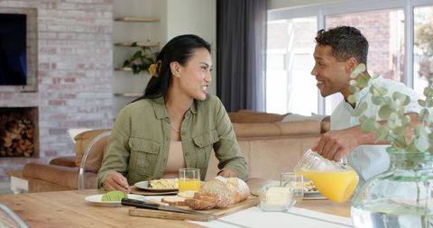 Couple Sharing Cozy Home Breakfast While Pouring Orange Juice and Smiling