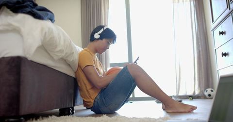 Asian student studying at home with headphones and tablet