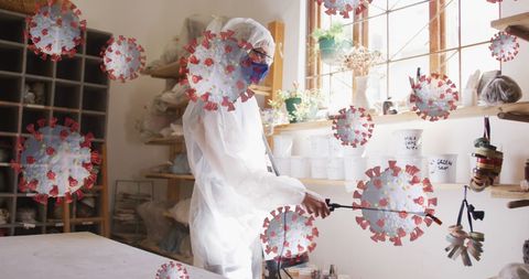 Person in protective suit sanitizing room with virus cells overlay