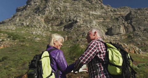 Hiking Couple Consulting Map on Rocky Mountain Path