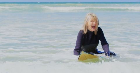 Joyful Senior Woman Riding Waves on Surfboard at Sunny Beach