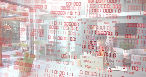 Asian remote developer working on laptop with red binary overlay in modern glass office