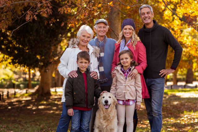 Portrait of smiling multi-generation family standing with dog at park during autumn