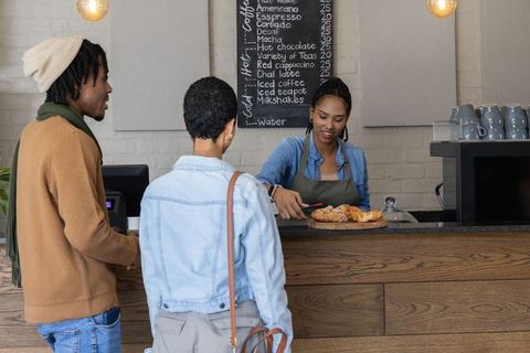African american barista serving pastries to customers at cozy cafe counter