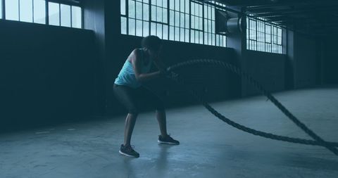Woman Exercising with Ropes in Abandoned Building Partial Light