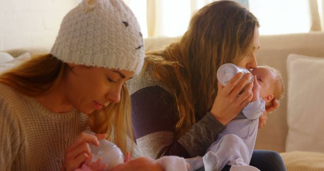 Two Mothers Bottle Feeding Infants on Sofa in Cozy Living Room - Download Free Stock Images Pikwizard.com