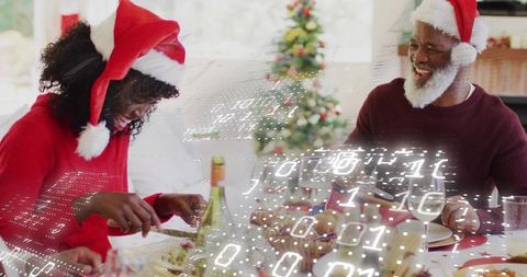 Family celebrating holiday dinner wearing santa hats with binary data overlay