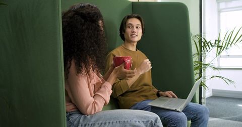 Coworkers engaging in casual discussion in modern office lounge