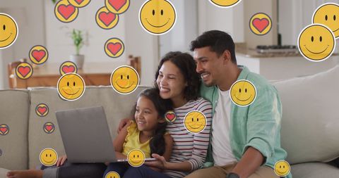 Happy family using laptop with floating emoji icons