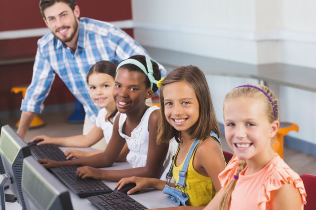 Teacher guiding diverse group of students using computers in classroom. Ideal for educational materials, school websites, technology in education promotions, and articles on modern teaching methods.