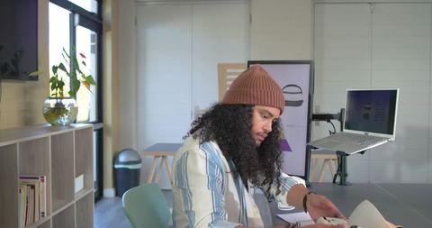 Designer sketching product concept at modern studio desk with laptop arm and monitor