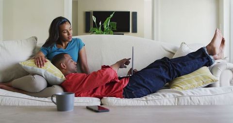 Happy Biracial Couple Relaxing with Laptop on Sofa