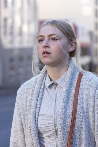 Young woman walking urban street wearing cozy knit cardigan and striped zip shirt