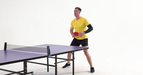 Male athlete preparing for table tennis game in studio