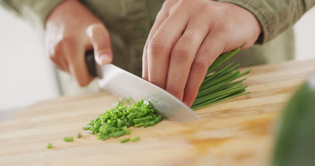 Image of hands of biracial woman cutting chives. Lifestyle, cooking and spending free time at home concept.