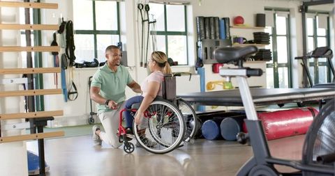 Physical Therapist Assisting Woman in Wheelchair with Rehabilitation Exercises