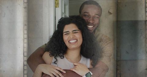 Couple embracing in doorway with retro film-strip overlay, woman smiling wearing smartwatch