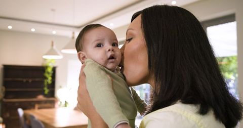 Mother kissing baby in cozy dining area