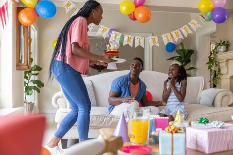 African american family celebrating daughter's birthday with colorful cake balloons gifts